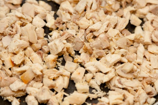 Diced chicken breast fried on large pan.