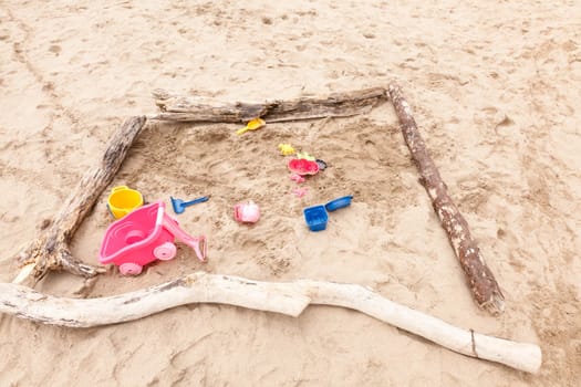Unorganized colorful plastic beach toys on sand .