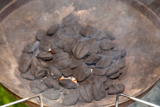 Brazier grill loaded with burning charcoal briquettes.