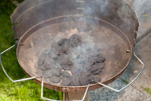 Brazier grill loaded with burning charcoal briquettes.