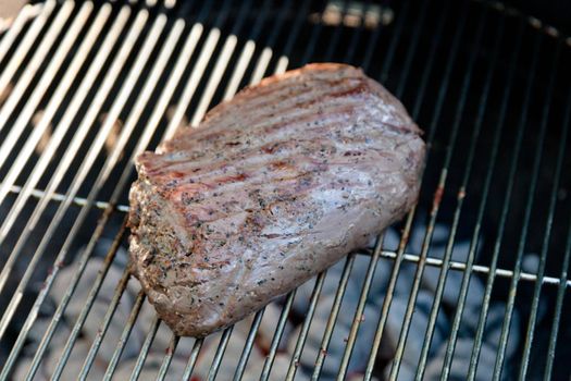 Meat cooking on a charcoal grill in a garden.