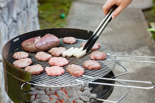 Meat cooking on a charcoal grill in a garden.