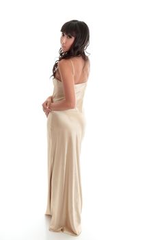 An attractive young woman wearing a long gold evening dress.  She is looking over her shoulder.  White background.