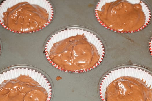 Preparing chocolate cupcakes for baking in oven.