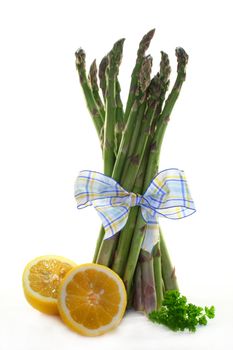 a bundle of green asparagus with lemon and parsley