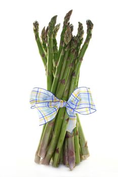 a bundle of green asparagus with ribbon on a white background