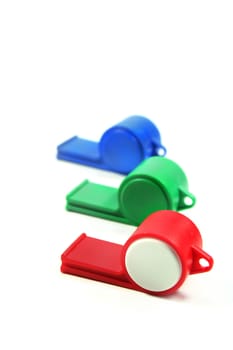 three colored whistles on a white background
