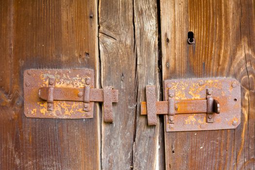 Rusty bar locks on wooden door of historic half-timbered house.