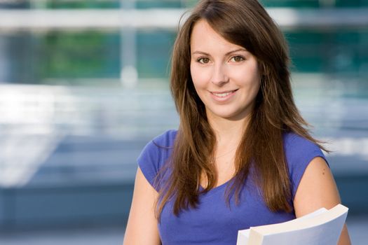 Pretty attractive caucasian white girl standing outside modern college school with books