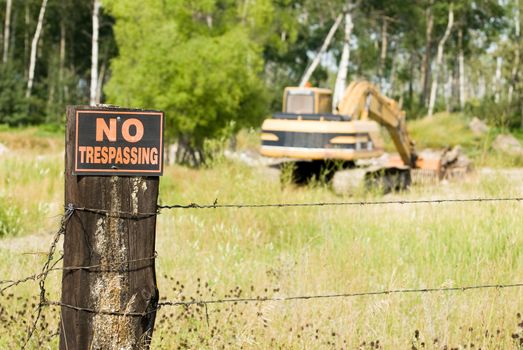 No trespassing at this work site featuring the sign and an excavator