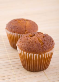 Two muffins on bamboo mat, close up, studio shot.