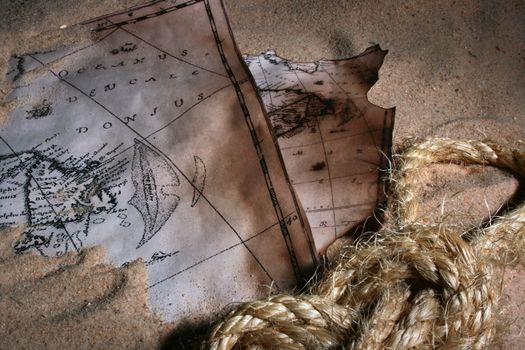 Old maps of coast of America on sand with a rope in the fastened sea knot.