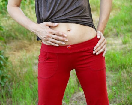 slim woman stomach in red sports clothes outdoors