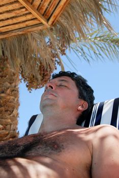 caucasian man portrait lying under sunshade on beach in Egypt