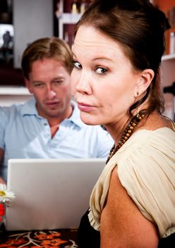 Handsome man using laptop ignoring his pretty date in coffee house