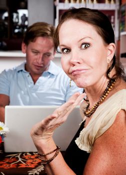 Handsome man using laptop ignoring his pretty date in coffee house