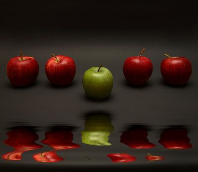 A line of apples with one exception.

(with water reflection)