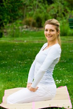 Blonde girl in nature green park exercising yoga, fitness program