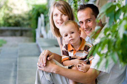 Happy perfect young family with dad, mom and son outdoors having fun