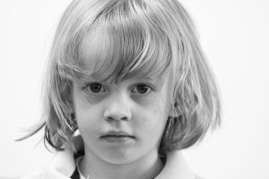 Cute young caucasian boy with blond hair looking serious