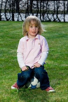 Cute young caucasian boy playing football or soccer outdoors