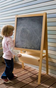 Cute young caucasian boy writing on a blackboard in school or kindergarten