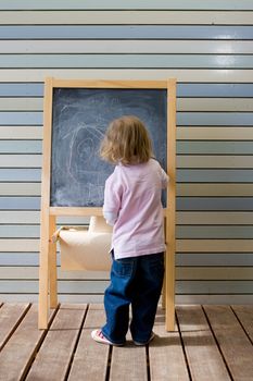 Cute young caucasian boy writing on a blackboard in school or kindergarten