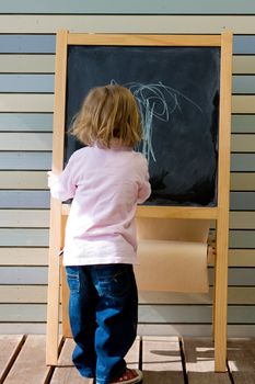 Cute young caucasian boy writing on a blackboard in school or kindergarten