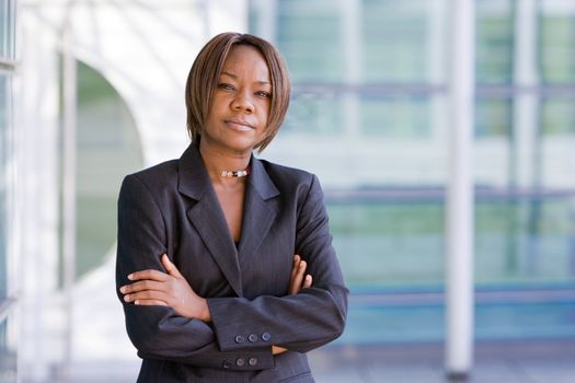 Black african american business woman posing in front of a modern office building with arms folded