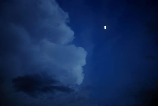 half moon glows on the face of the cloud