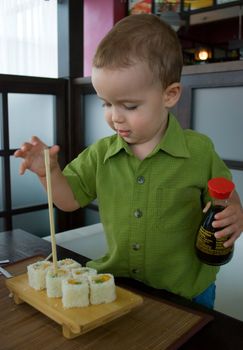 Little boy trying to eat sushi at a Japanese restaurant