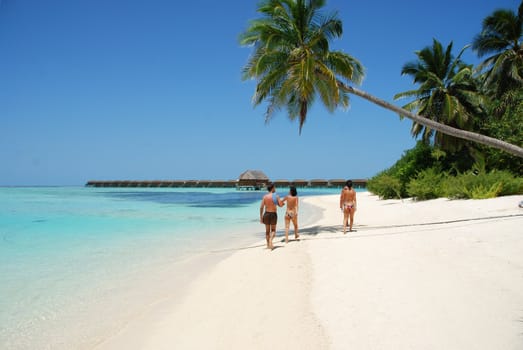 beautiful scene with a family walking by the beach in Maldives