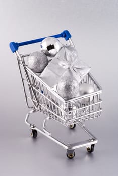 Shopping cart full christmas decoration, isolated on a silver background.