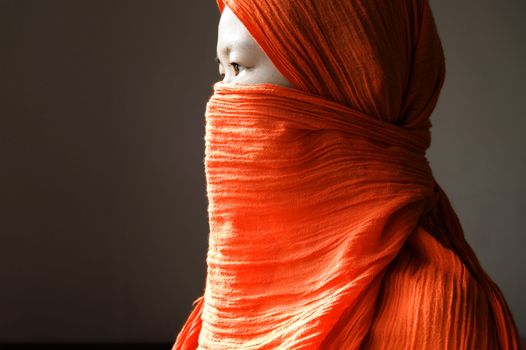 Close-up of a islamic woman covered with a orange veil 