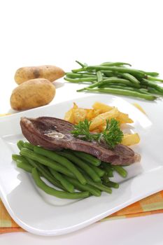 Lamb meat with pommes frites and green beans on a white background