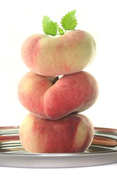 a stack of fresh mountain peaches with lemon balm on white background