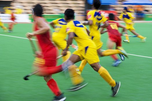 Image of men's field hockey players in action. Image intentionally blurred to portray speed.