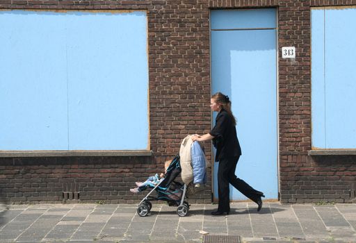 Girl with buggy walks past houses marked for demolition