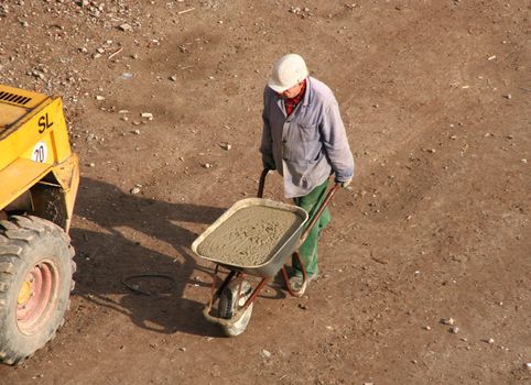 Construction worker pushes wheel barrow