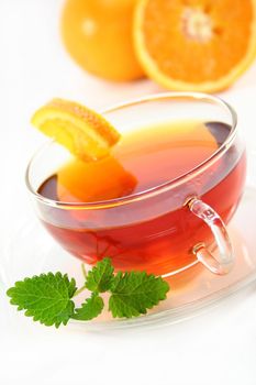 a cup of orange tea with fresh oranges and lemon balm