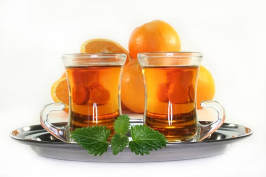 two glasses of orange tea and fresh oranges