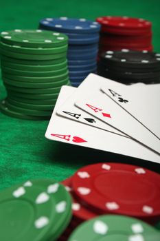 Four aces with gambling chips over green felt
