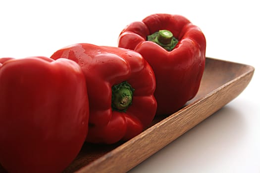 Three red pepper on a wooden plate - salad components.