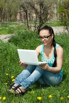 Photo of a girl with a laptop, on a background of flowers and green grass