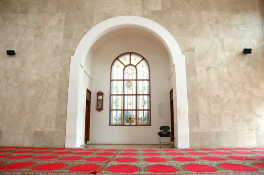 masjid hall with red carpet and white marble wall
