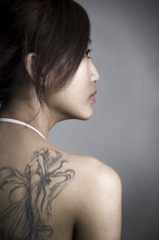 rear view of adult woman with tattoo, low key. 