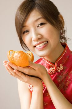 Pretty asian with cheongsam wear holding a mandarin orange