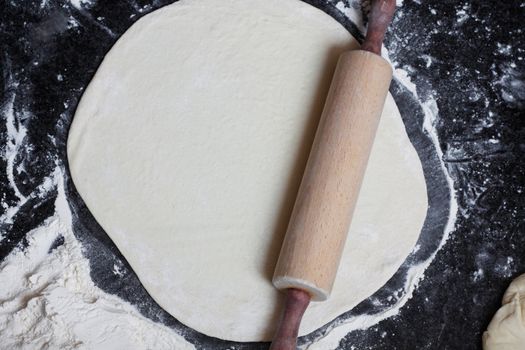 A rolling pin flattening a pizza