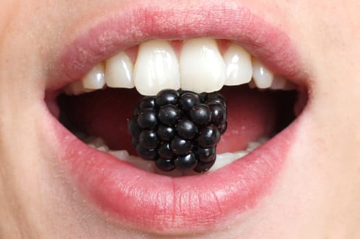 A mouth with a blackberry in it