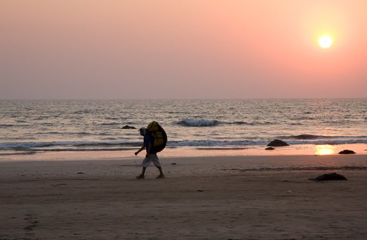 Sunset on the beach with tourist with big backpack